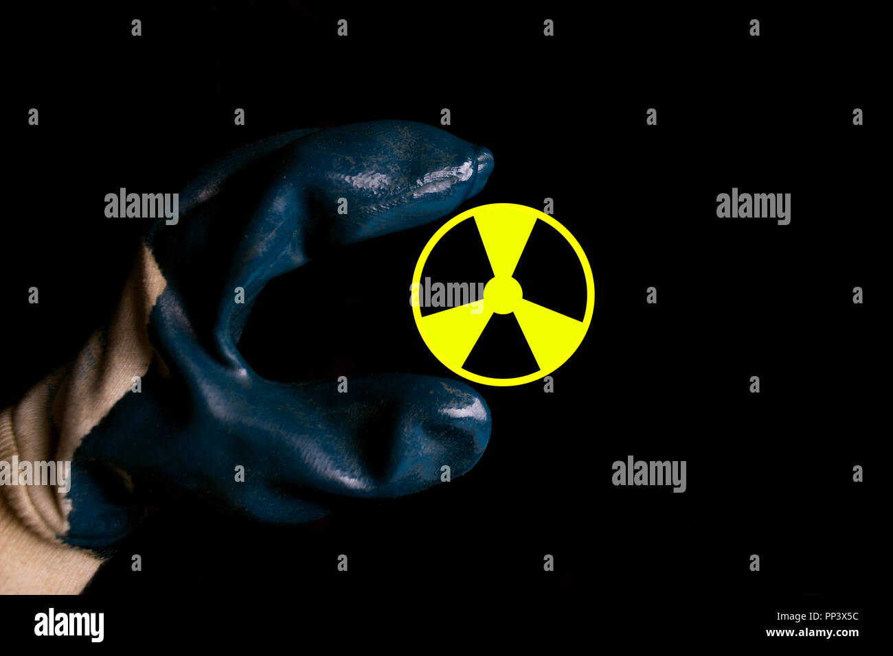 A hand holding a symbol for radioactivity on black background Stock Photo