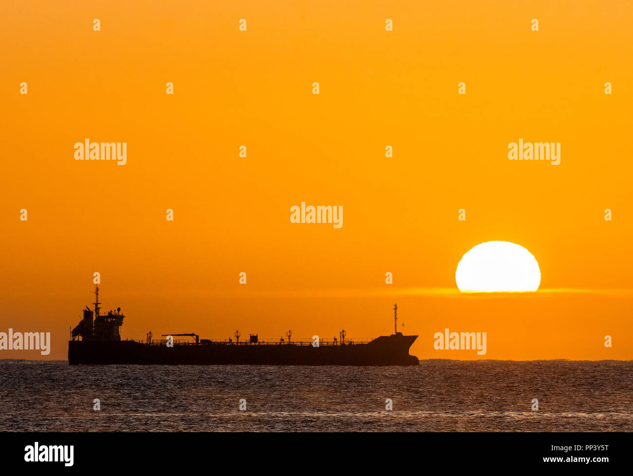 Crosshaven, Cork, Ireland. 25th September, 2017. Oil tanker Thun Galaxy silhouetted by the rising Sun while at anchor outside Cork Harbour, Ireland.- Stock Photo