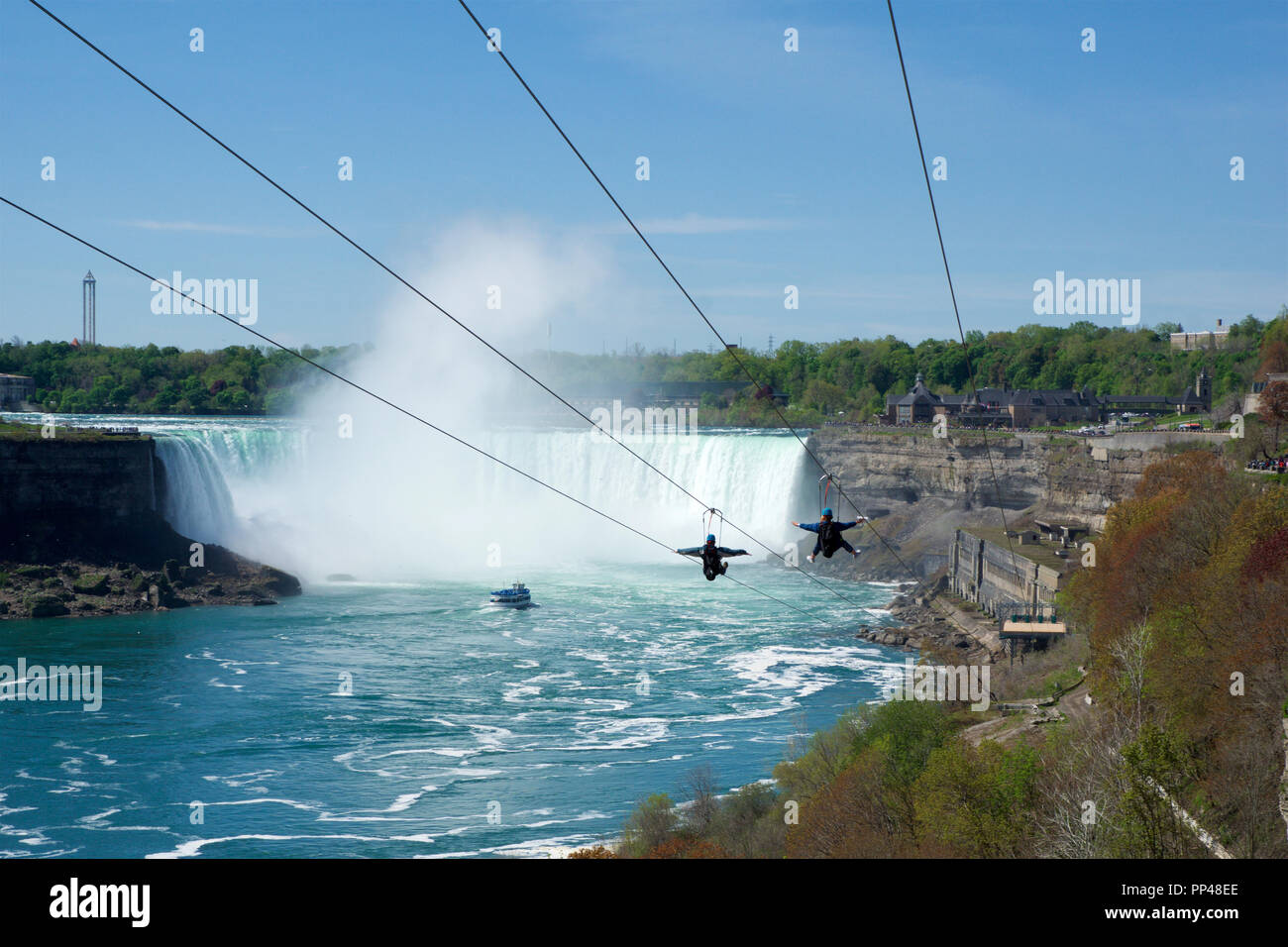 NIAGARA FALLS, ONTARIO, CANADA - MAY 21st 2018: Two people taking zipline ride at Niagara Falls in summer with Horseshoe Falls in background Stock Photo