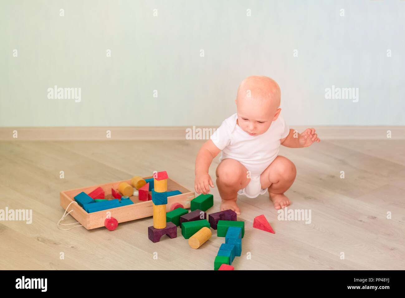 Cute little baby playing with colored wooden blocks in the room. Early ...