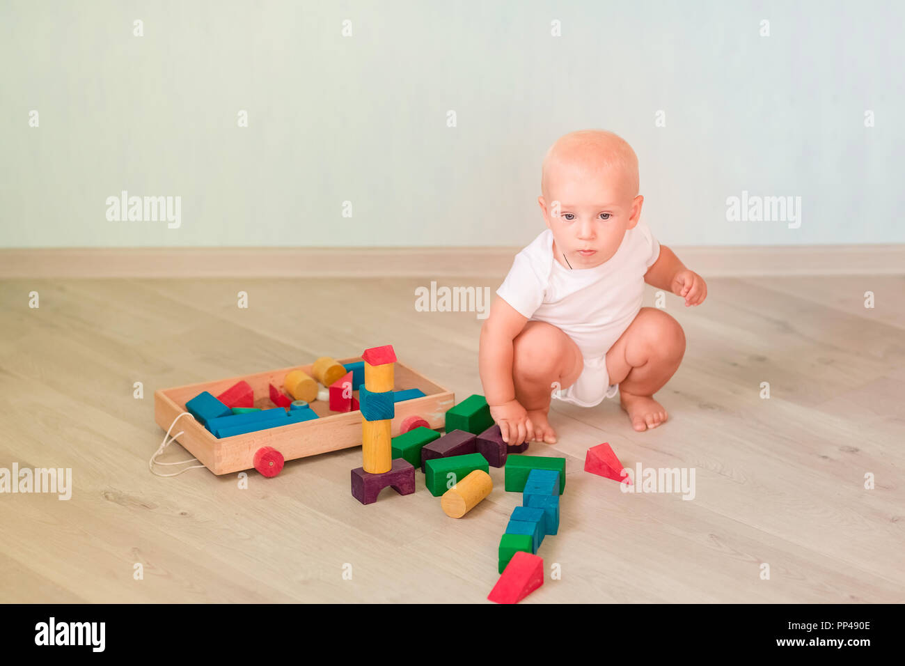 Cute little baby playing with colored wooden blocks in the room. Early ...