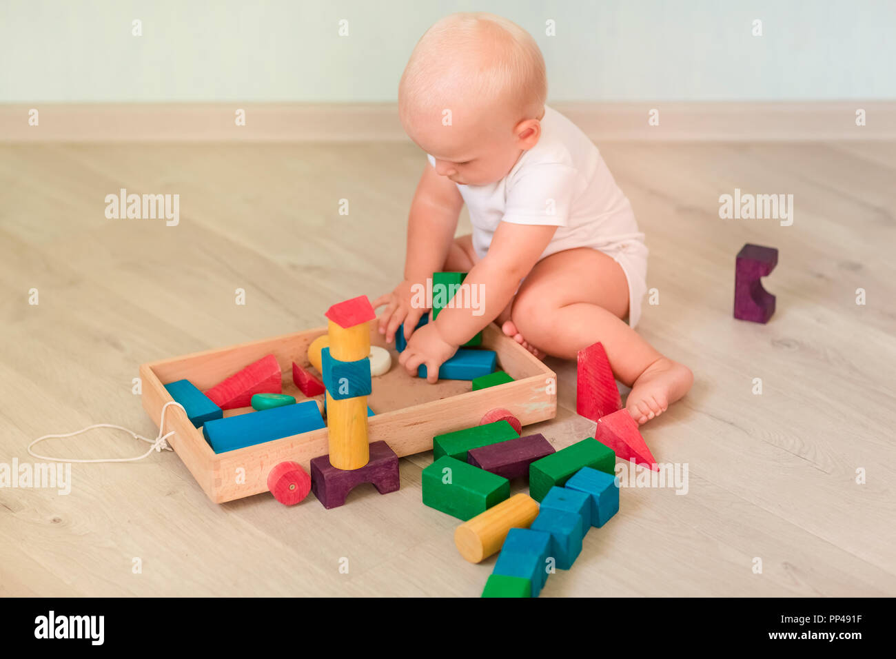 Cute little baby playing with colored wooden blocks in the room. Early ...