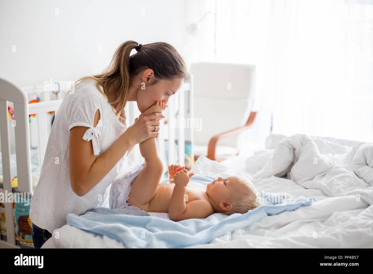 Young mom, changing baby diaper after bath in sunny bedroom Stock Photo Alamy