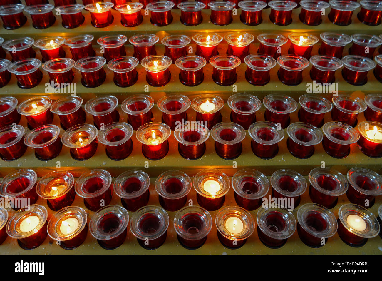 Many lighted candles in candlesticks. Sacred light. Burning candles in church. Concept of religion. Bright yellow light in the evening, close-up Stock Photo