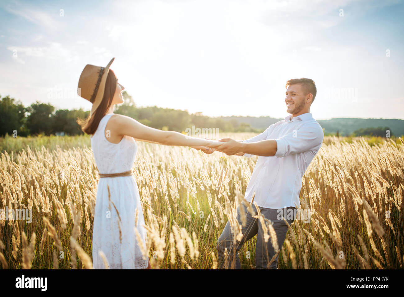 Love couple hold hands, walking in a rye field. Cute family on summer meadow Stock Photo