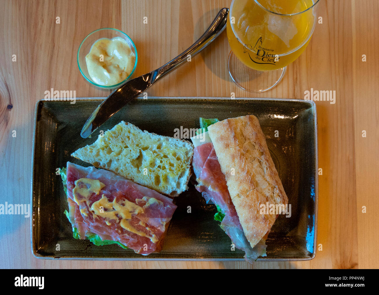 Ham and cheese sandwich on French bread with Dijon Mustard and a glass of beer at a bistro in Montreal, QC, Canada Stock Photo