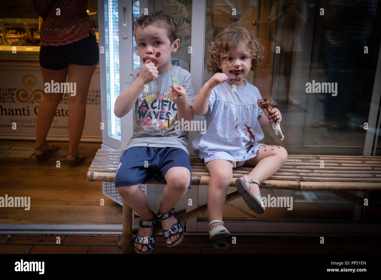 Barcelona, Spain. 22 September 22, 2018: Two children with get chocolate ice cream all over their faces and clothes while sitting in the street Credit: On Sight Photographic/Alamy Live News Stock Photo