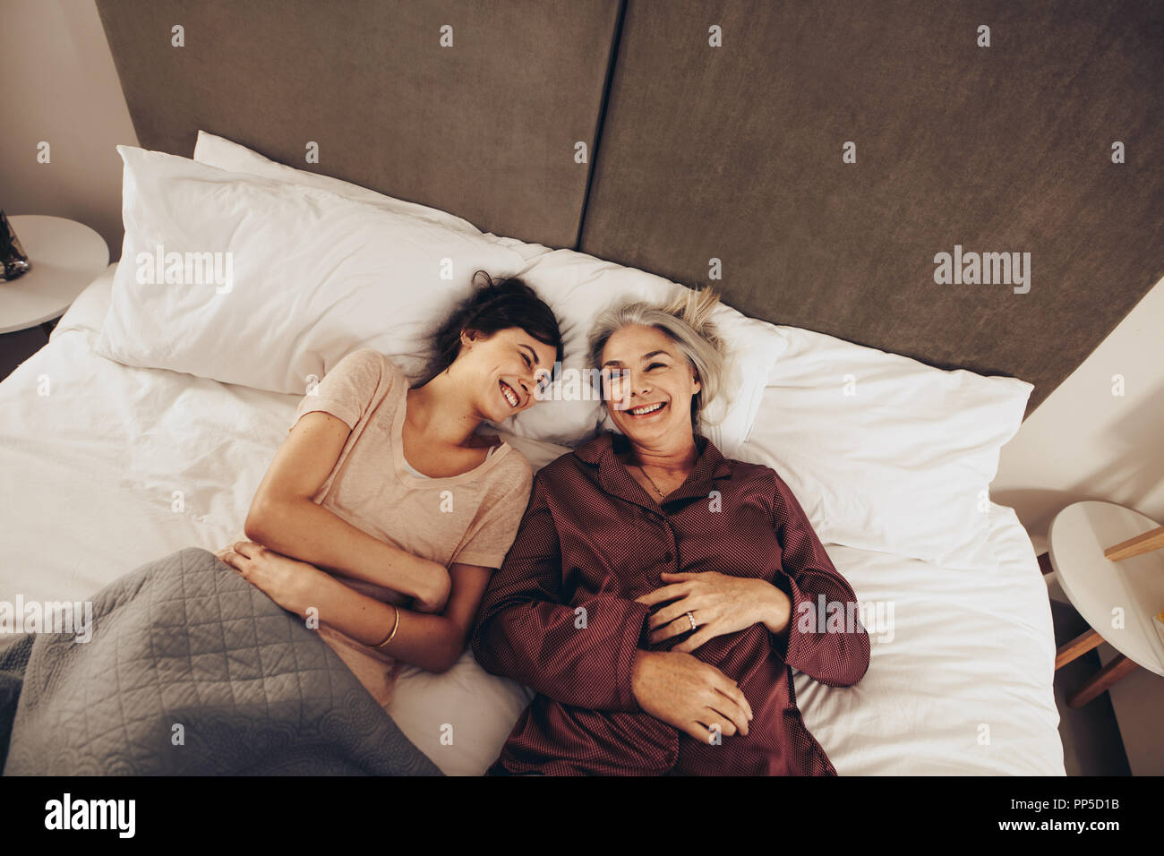 Senior woman lying on bed with her daughter and talking. Happy woman
