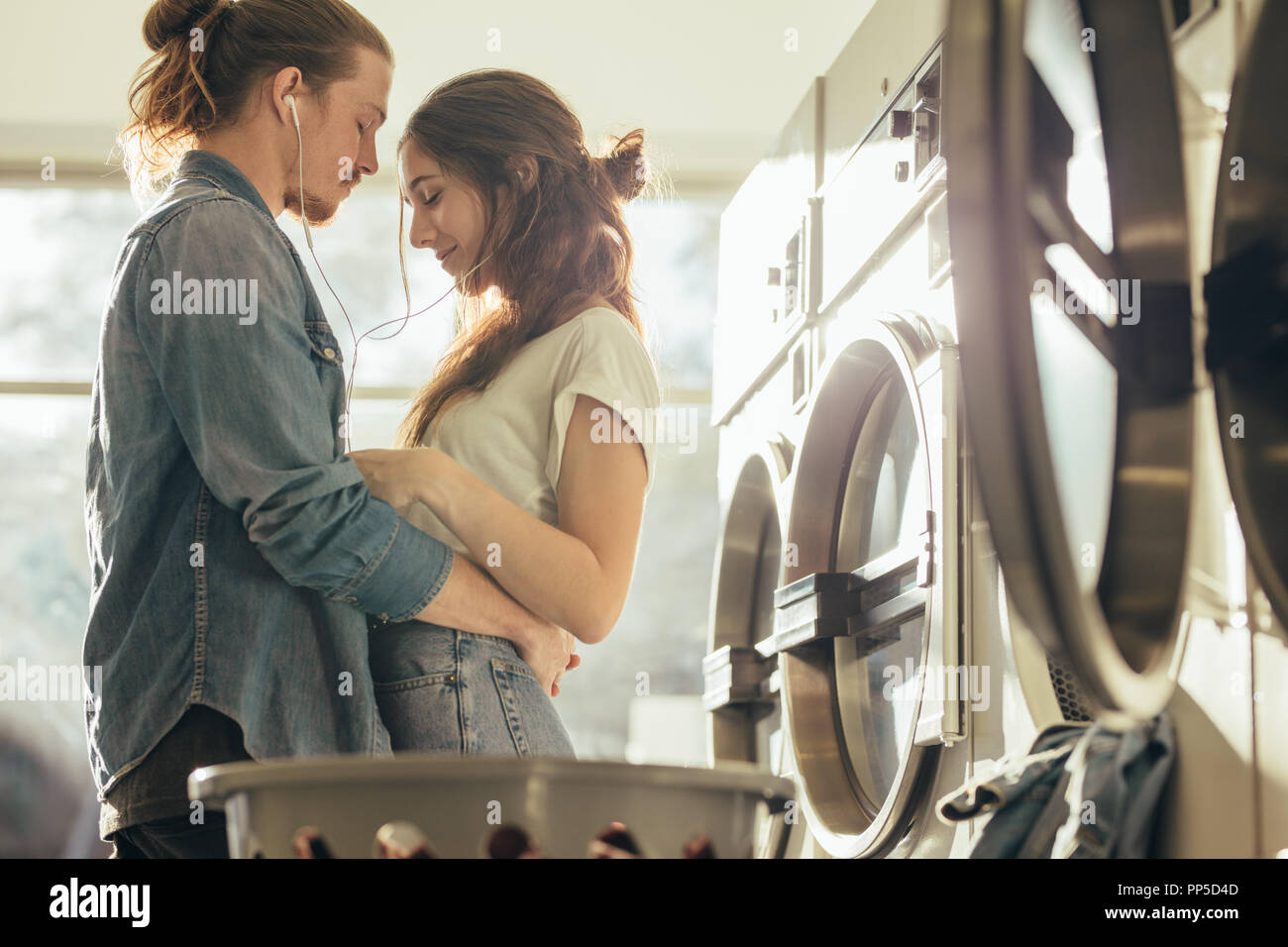 Couple Standing Facing Each Other In A Laundry Room With Closed Eyes Couple Listening To Music