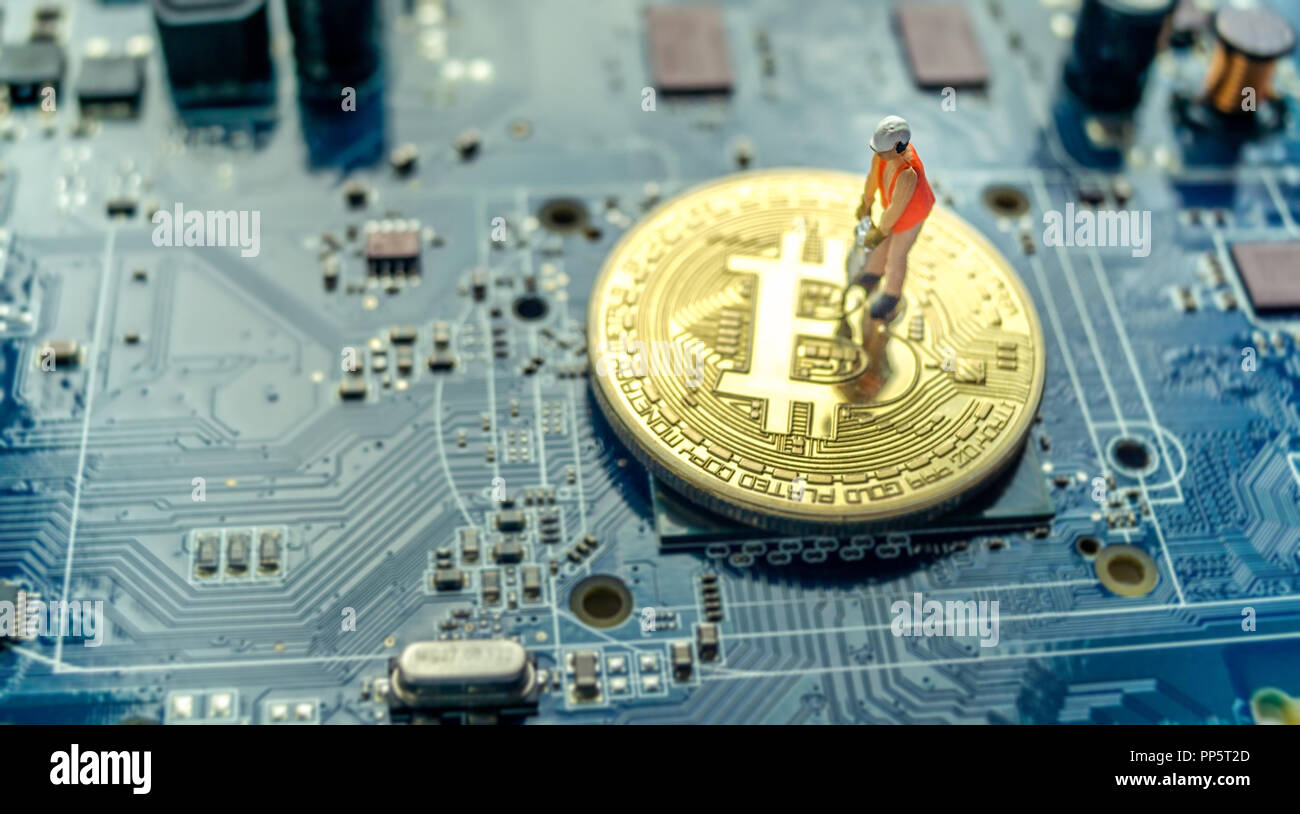Miniature construction worker standing on physical Bitcoin, mining concept Stock Photo