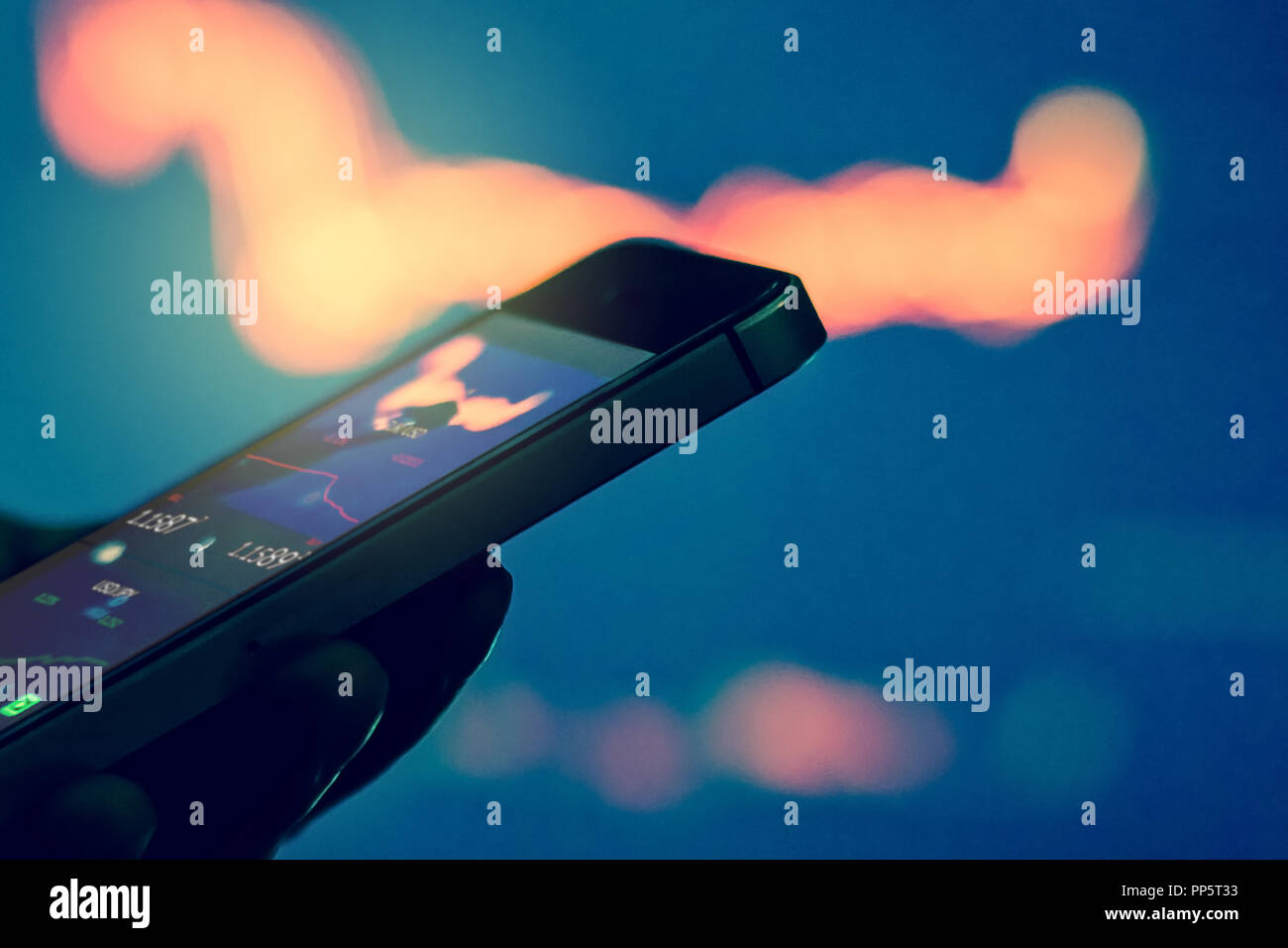Trader in dark using mobile phone against stock market charts Stock Photo