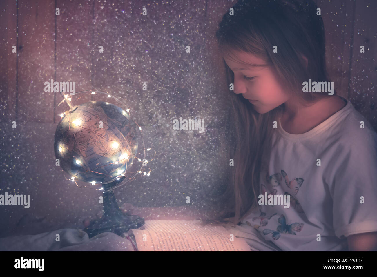 Admiring kid  girl reading  book in bed dreaming about space and universe concept astronomy curiosity knowledge education development Stock Photo