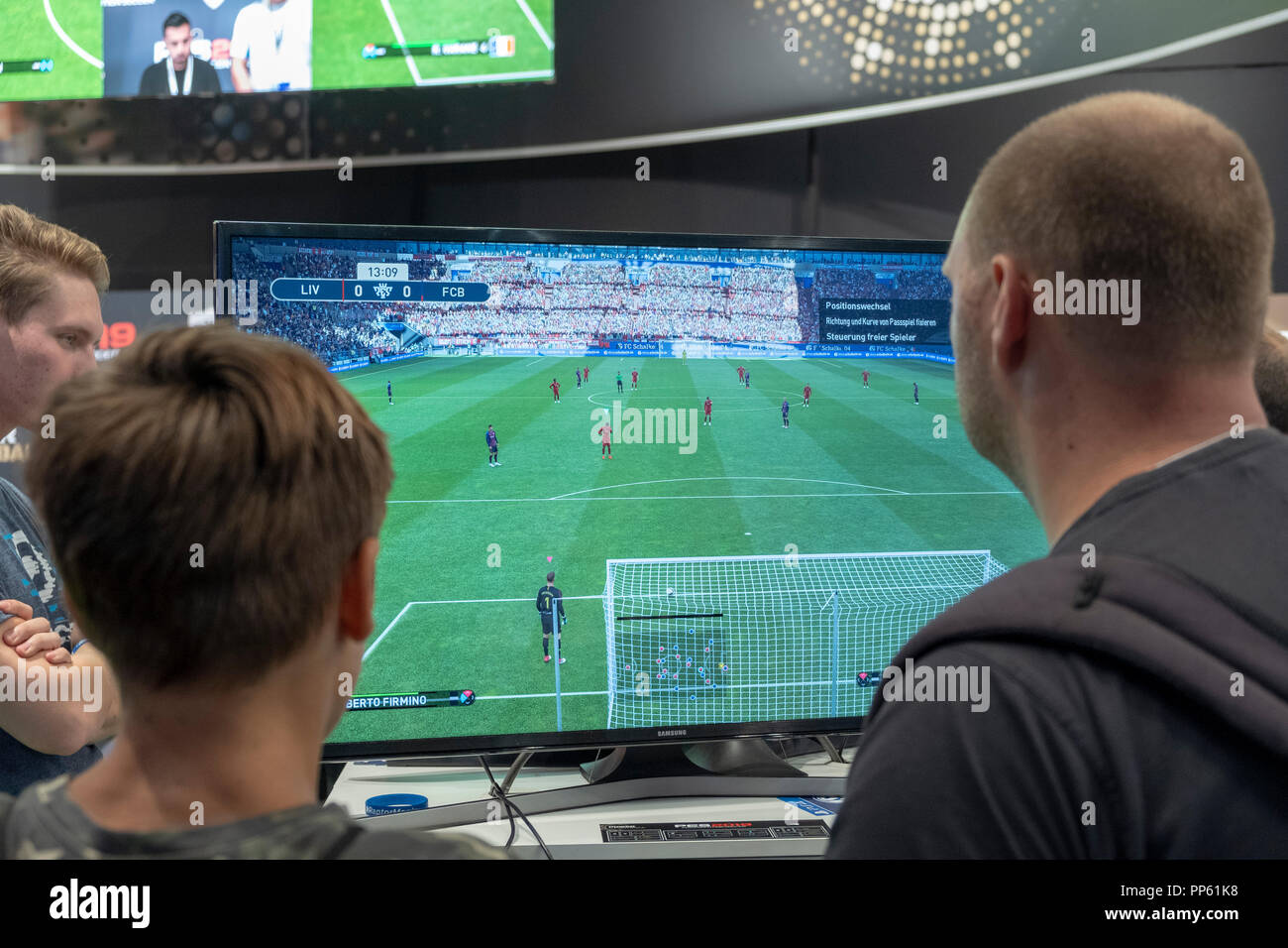 Visitors play the football simulation game PES 2019, Pro Evolution Soccer 2019 at Gamescom, the worlds largest computer and video games fair in Cologne, Germany on 24.8.2018 Stock Photo