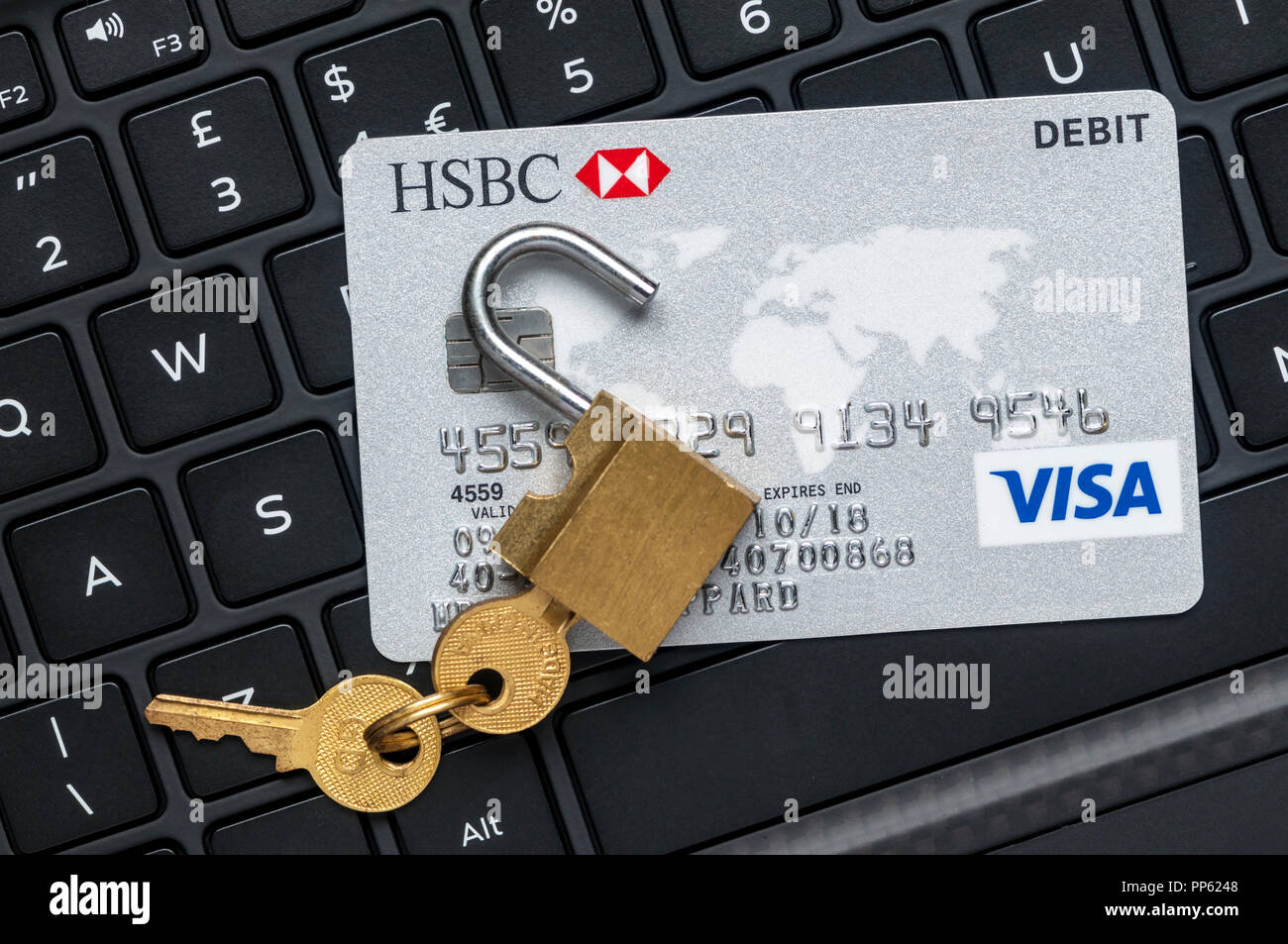 Unlocked padlock and debit card on a computer keyboard.  Online financial security concept.  NB: Data anonymised. Stock Photo