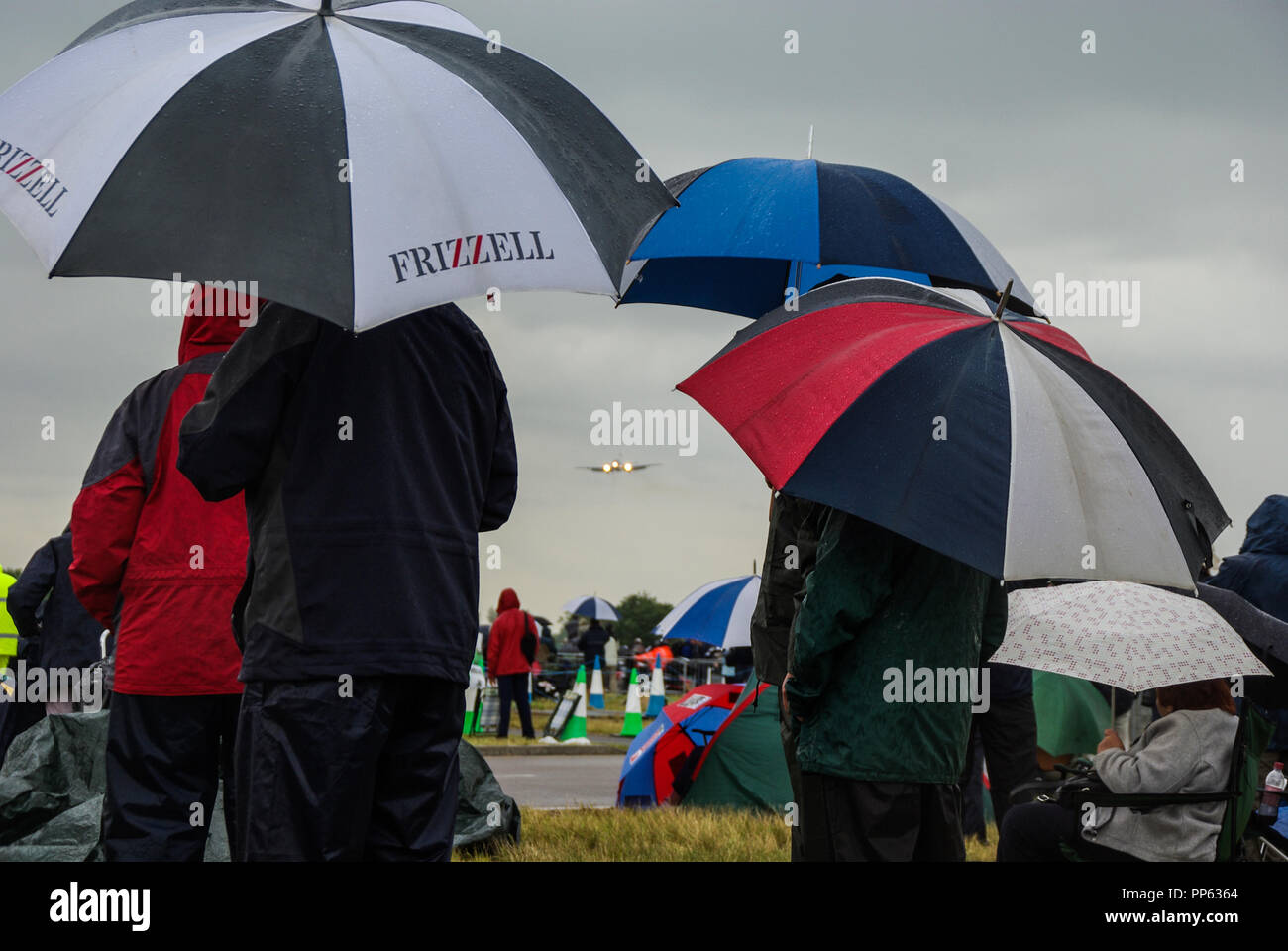 Wet aviation enthusiasts in the rain at an airshow as a RAF Nimrod jet ...