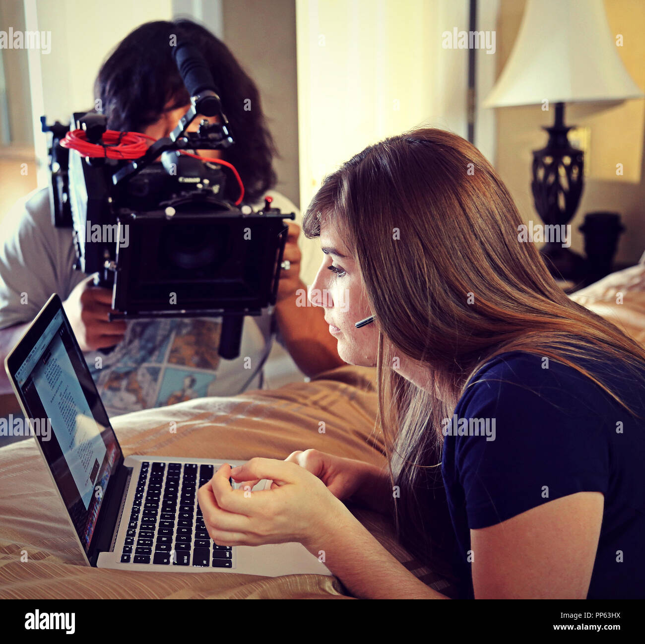 Production still from a short film. Cinematographer captures hand-held footage of a woman working on her laptop computer. Stock Photo