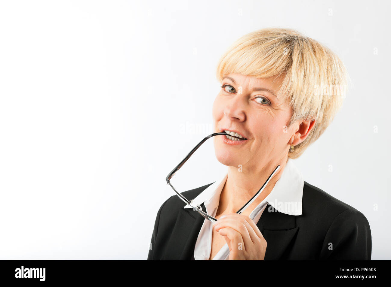 Mature businesswoman with eyeglasses earpiece in mouth Stock Photo