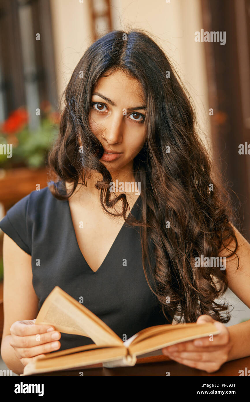 young Arabic woman reading a book in a cafe Stock Photo