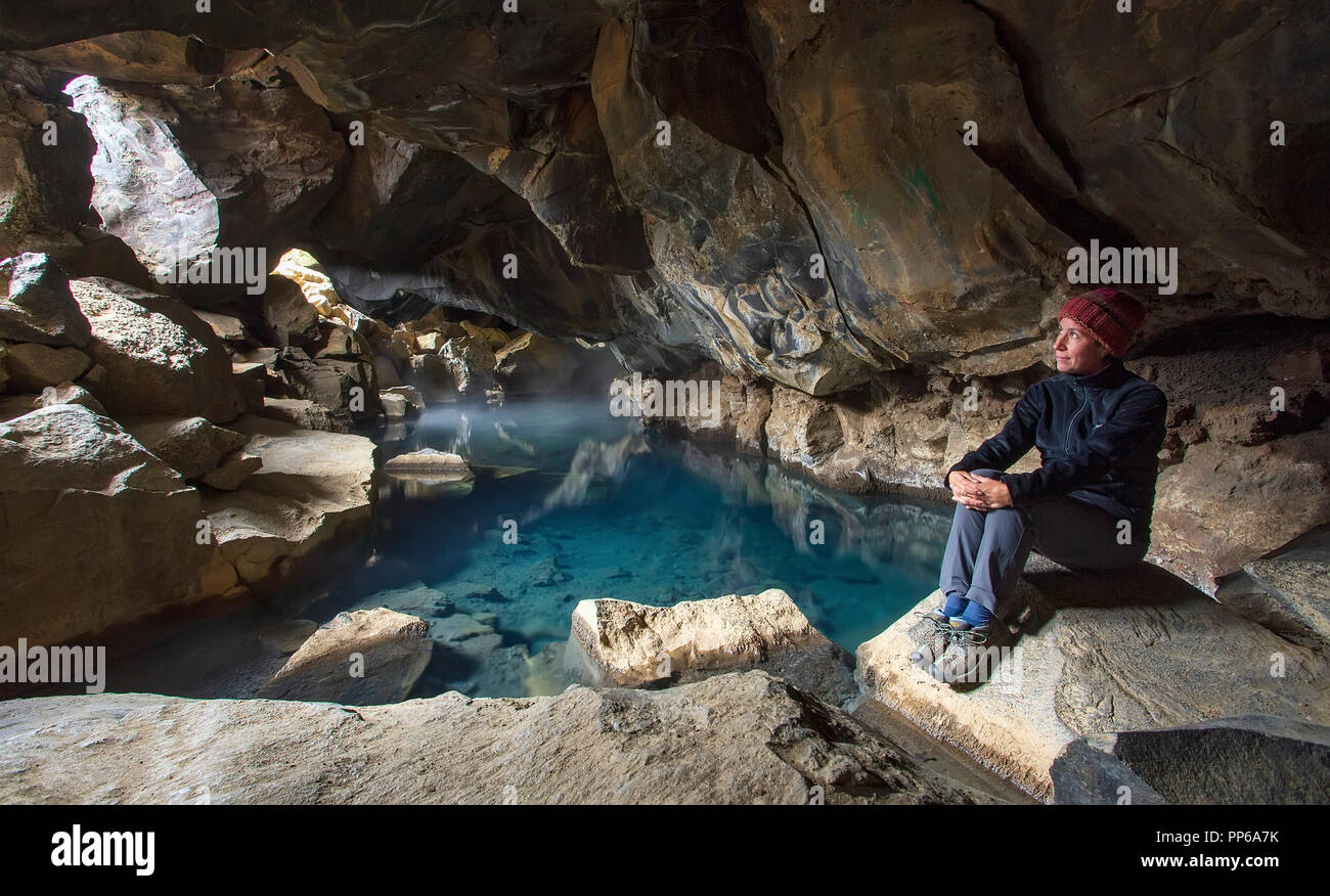 A woman sits by a geothermal pool in Grjótagjá cave, Iceland (aka the 'Game of Thrones' cave). Stock Photo