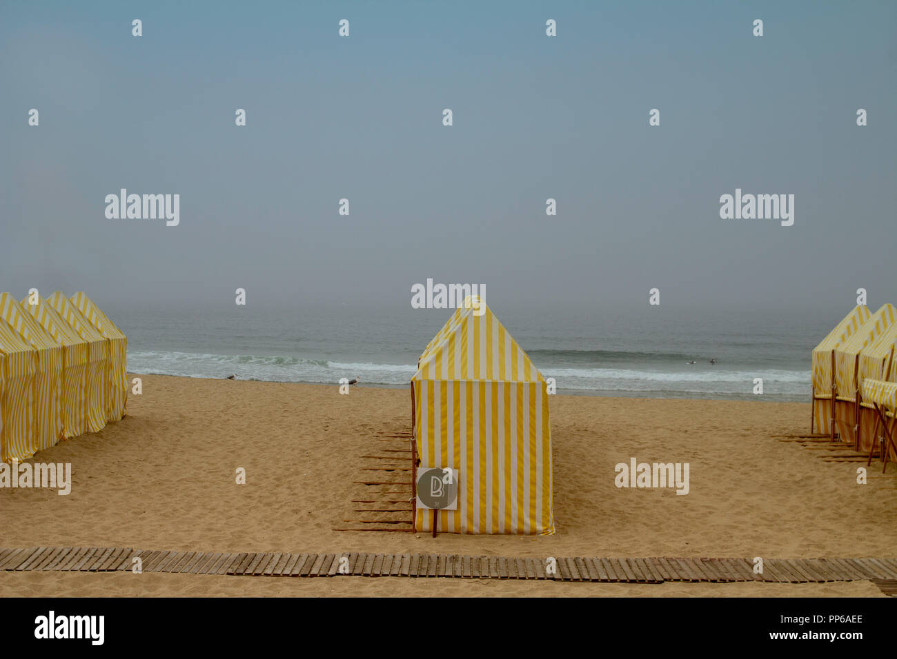 Espinho, Portugal. Deserted beach scene with beach huts and no sign of human activity on a hazy sunny day. Stock Photo