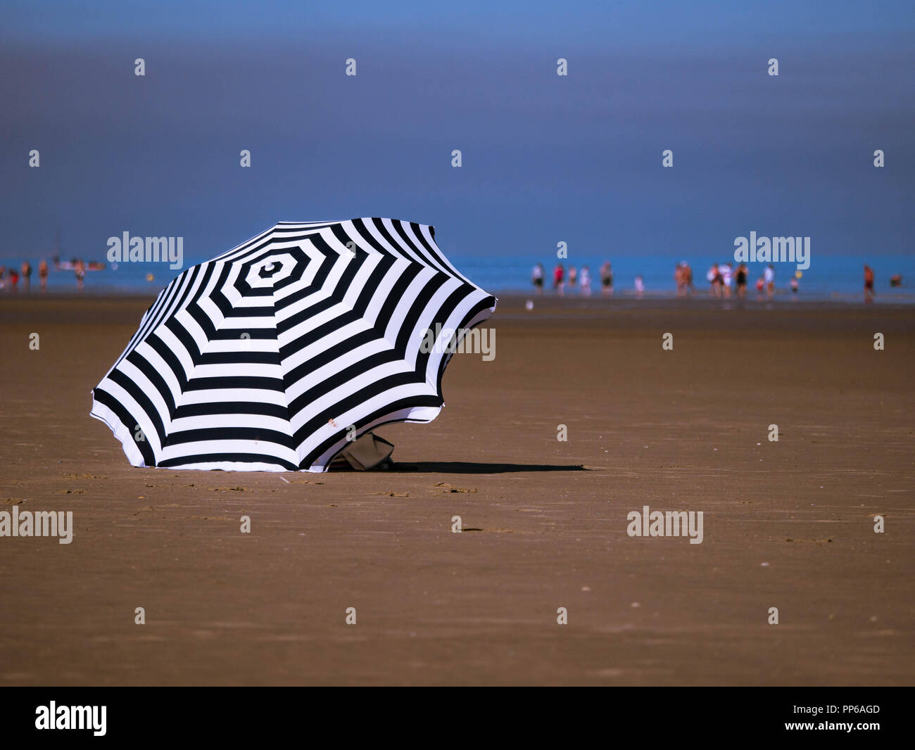 Umbrella in the foreground at the beach on a sunny day Stock Photo