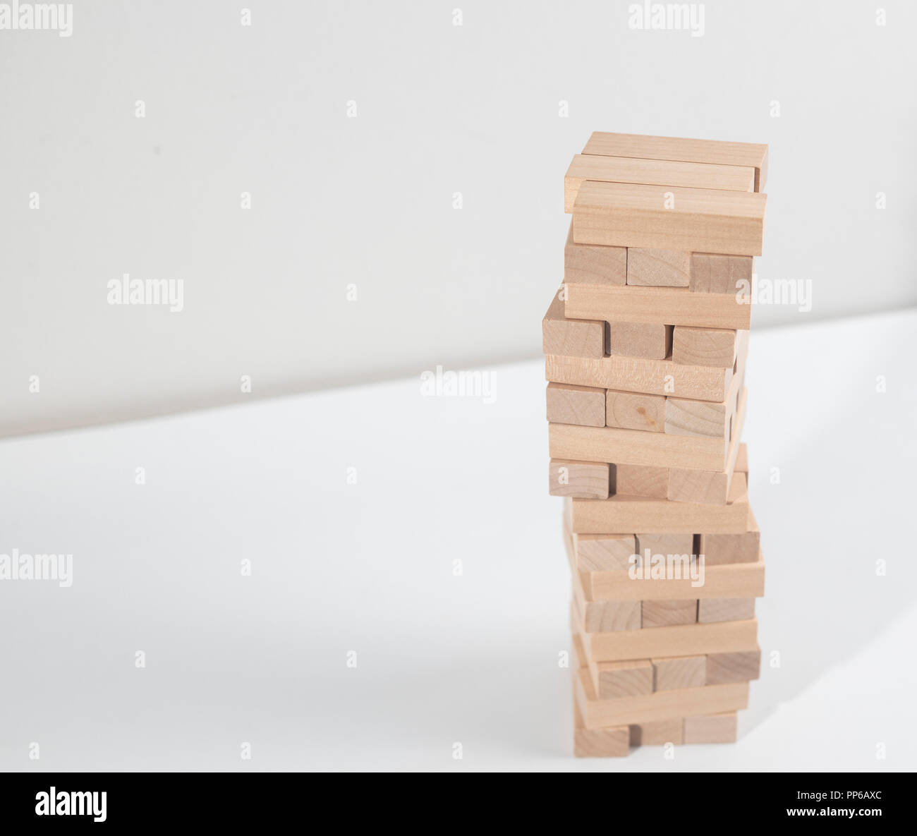 Jenga tower collapses on the white background on the table Stock Photo