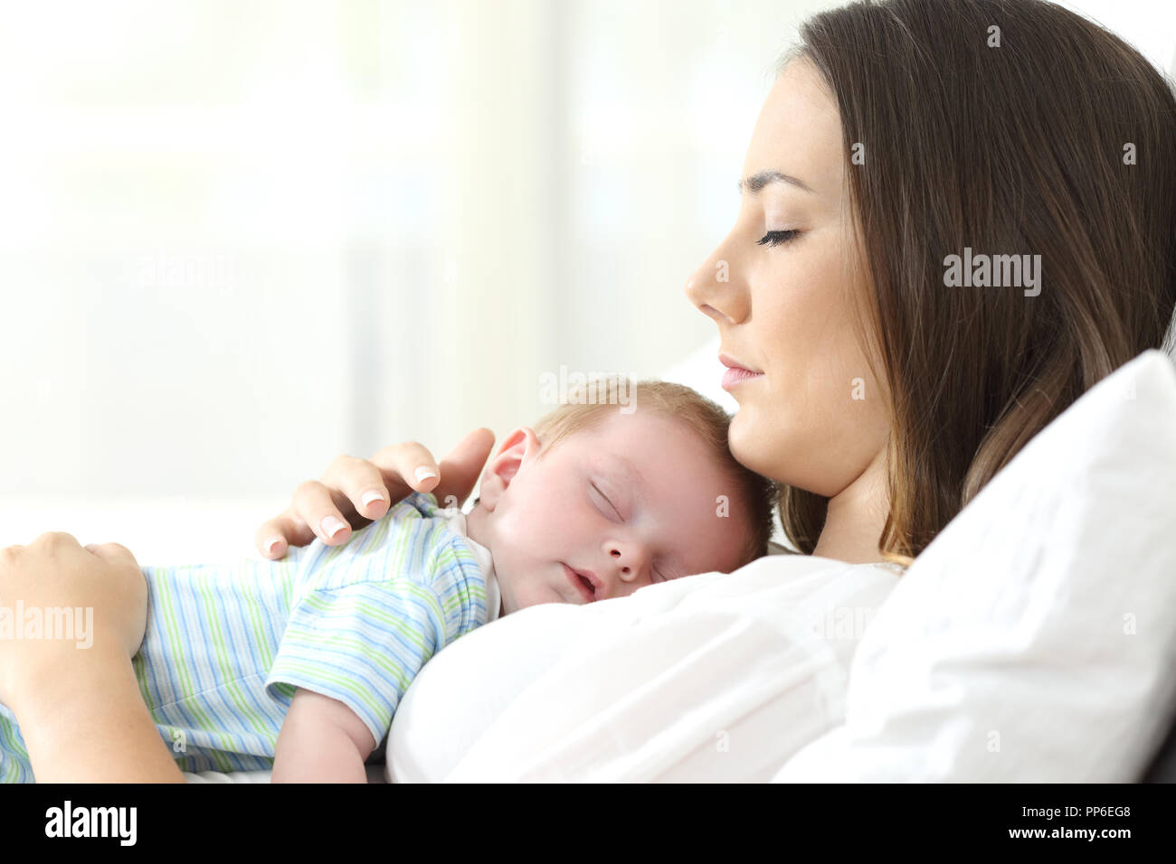 Profile of a serious mother sleeping with her baby on a bed Stock Photo
