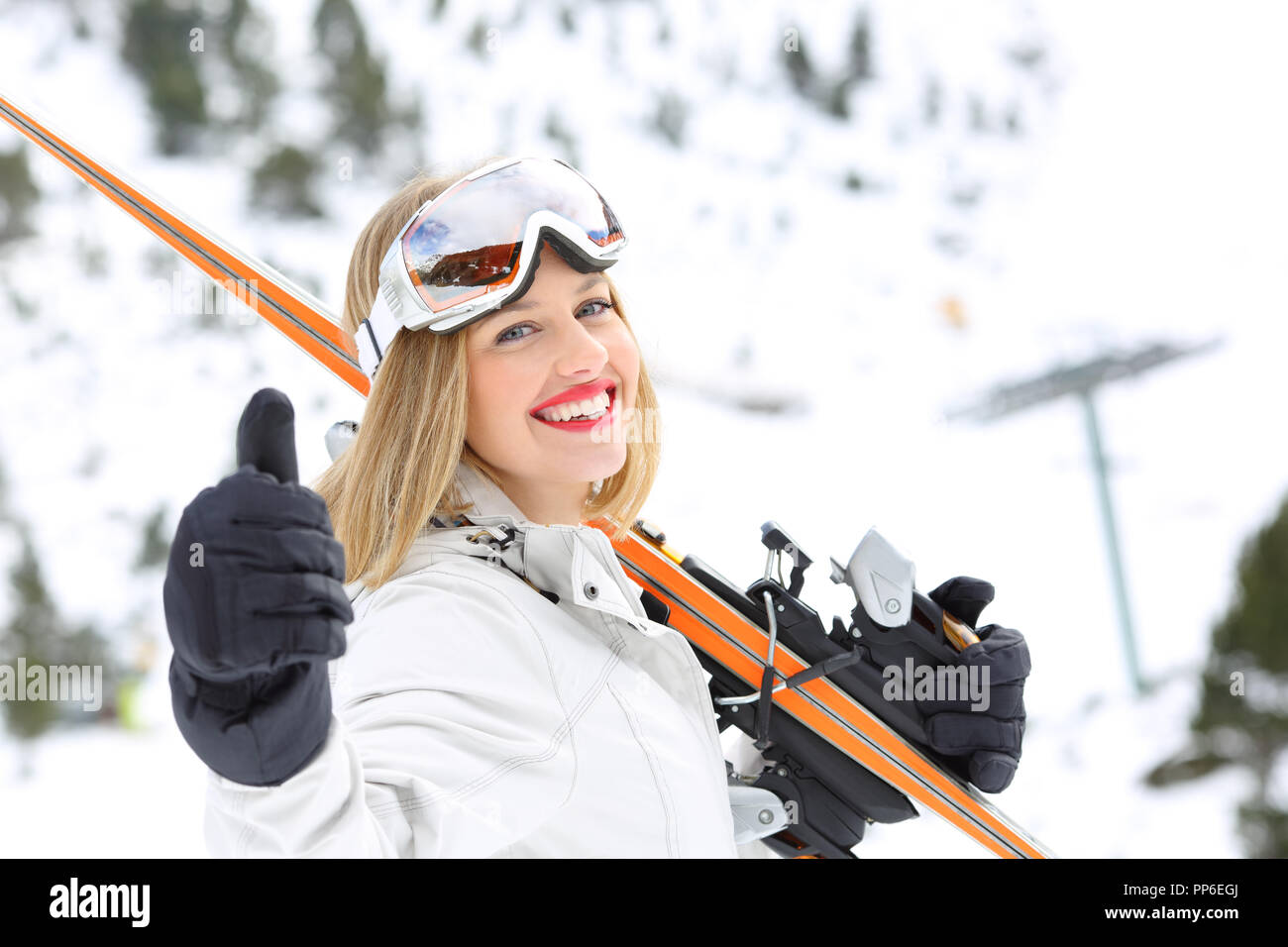 Skier ready to sky looking at camera with thumb up in a snowy mountain Stock Photo