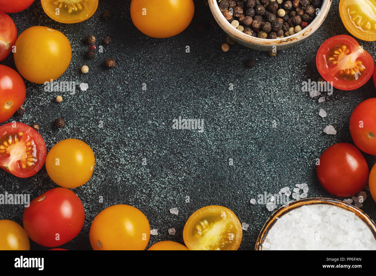 Fresh cherry tomatoes on a black background with spices. Top view with ...