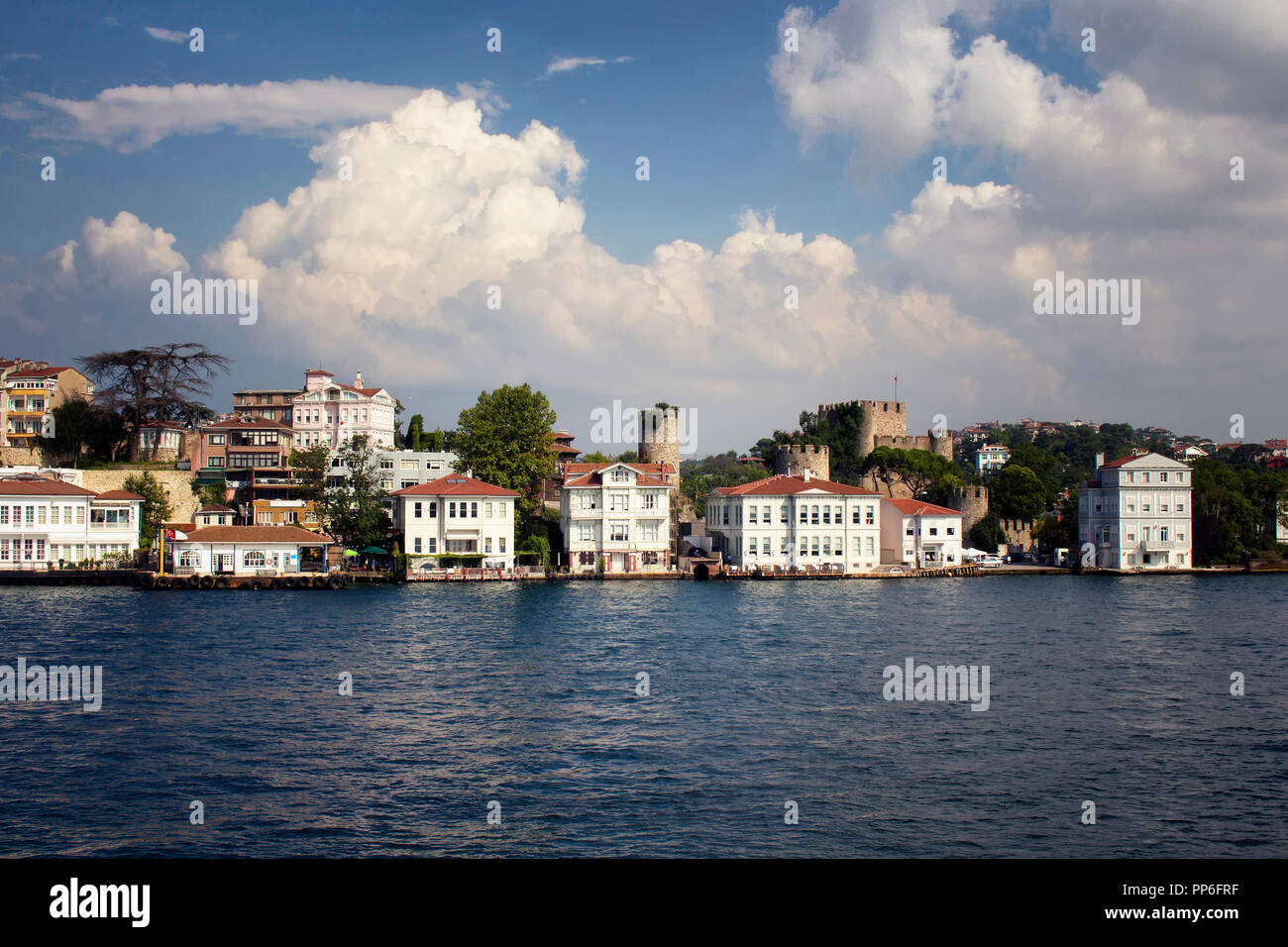 View of historical, old Turkish / Ottoman houses and a castle by Bosphorus on Asian side of Istanbul. It is a sunny / cloudy summer day. Stock Photo
