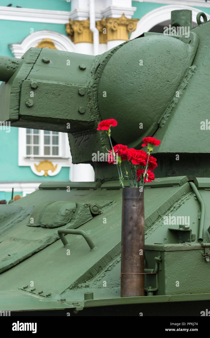 Bright red carnations on a green background of the Soviet T-34. Stock Photo