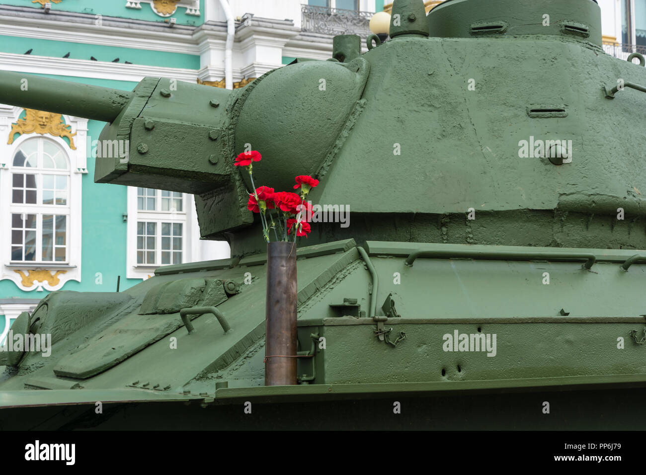 Bright red carnations on a green background of the Soviet T-34. Stock Photo