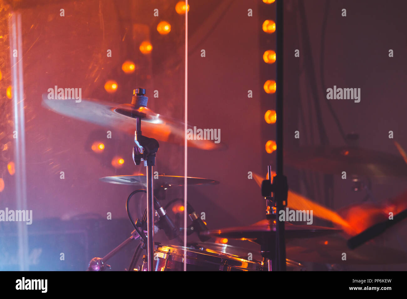 Live rock music colorful background, drummer plays with drumsticks on rock drum set. Warm toned closeup photo, soft selective focus Stock Photo