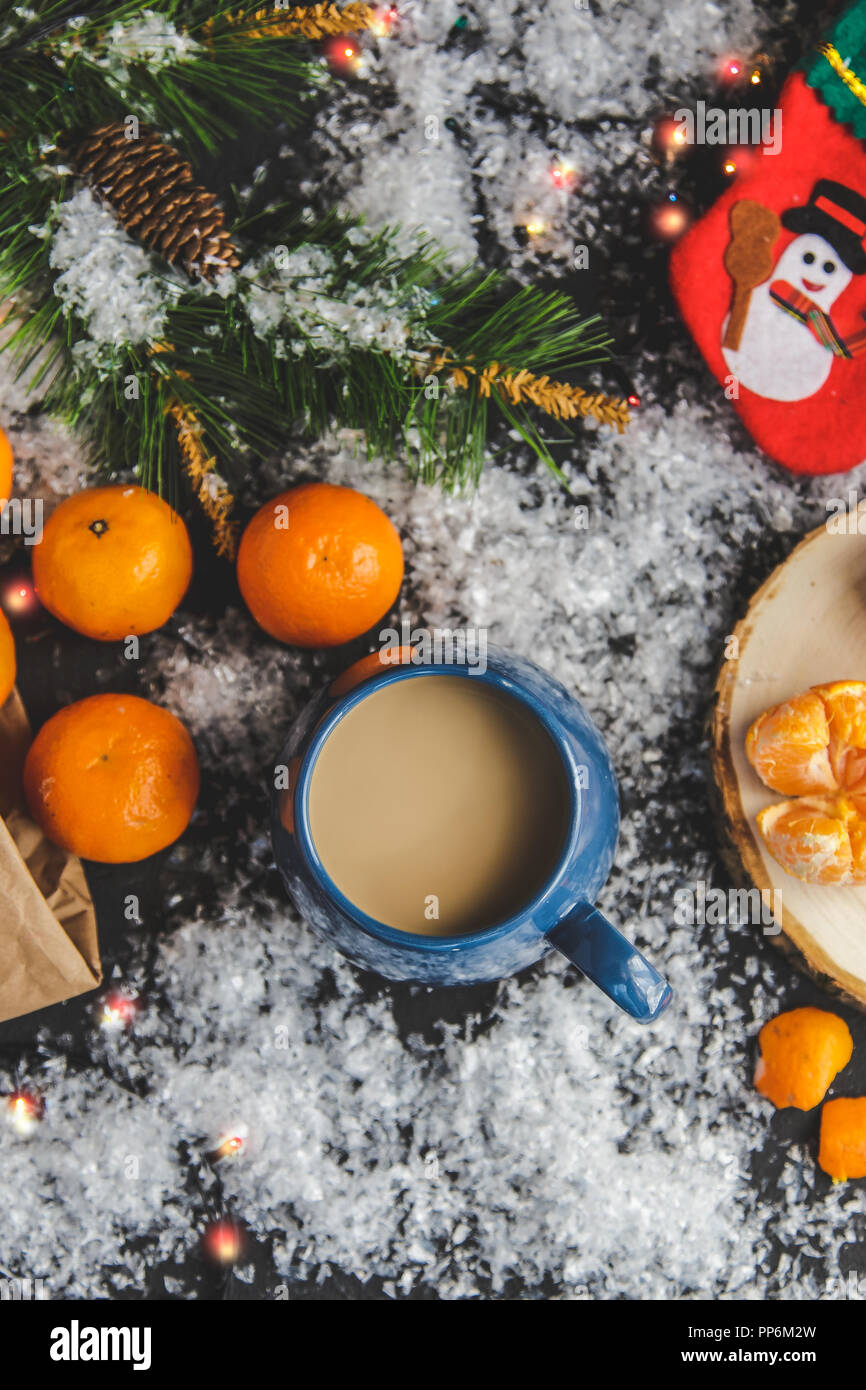 Christmas and New Year's concept. Mandarins, coffee mug, snow, Christmas tree branch. Against a dark background. Flat lay Top view Stock Photo