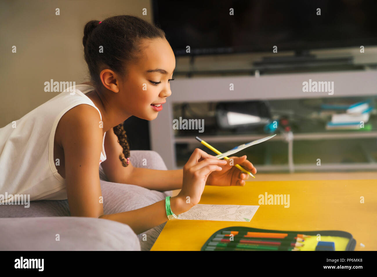 Tween girl drawing with colored pencils in living room Stock Photo