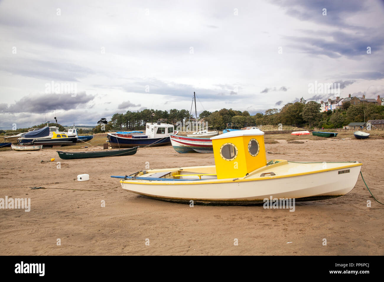 Small fishing boats on the beach at low tide in the Aln estuary at the ...