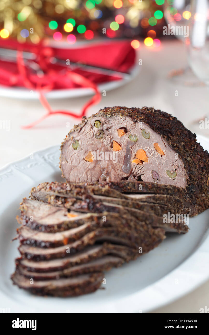 Roast beef larded with carrot and celery on the Christmas table. Shallow DOF Stock Photo