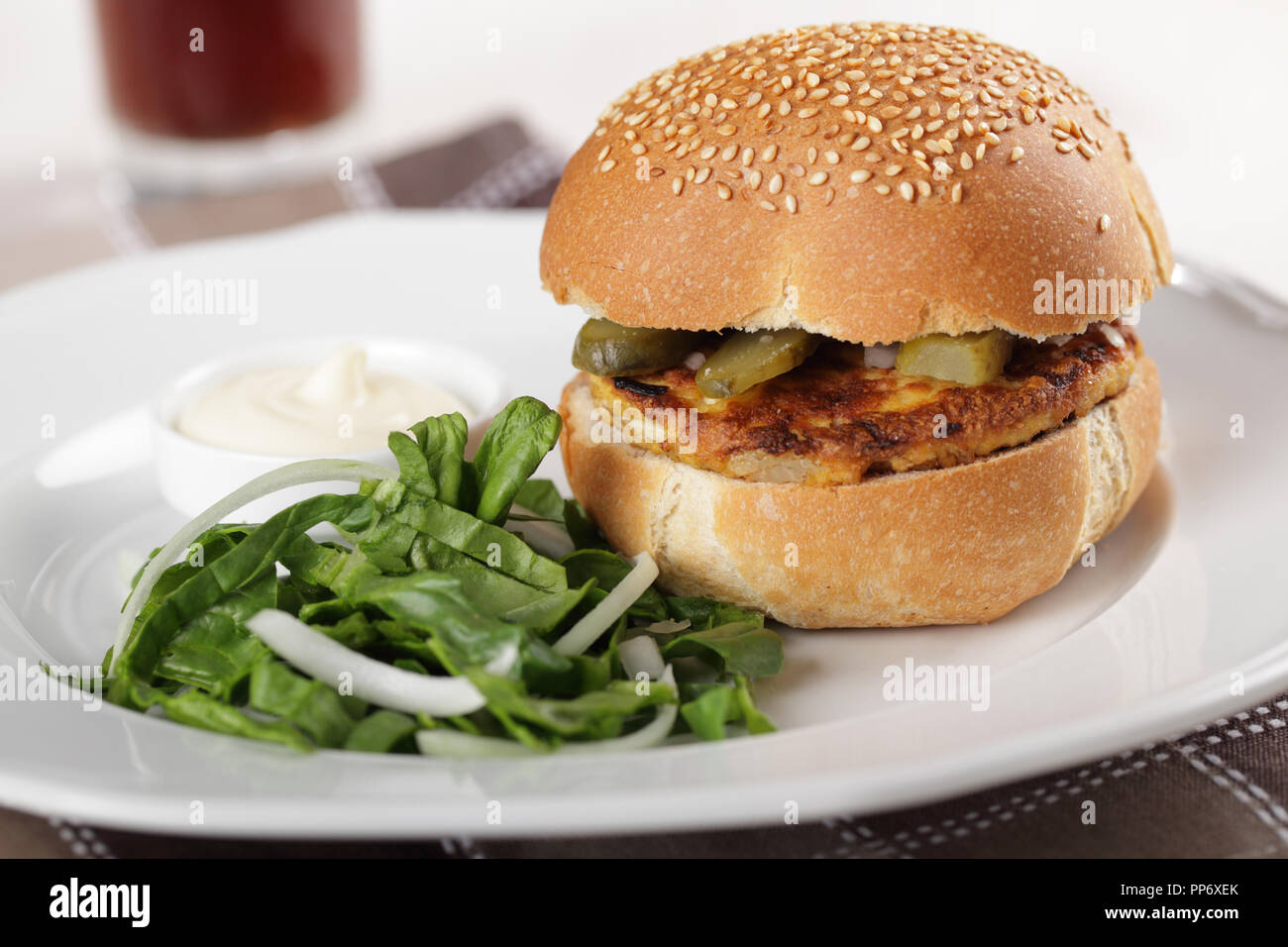 Veggie burger with fried tofu, pickled cucumbers, onion, spinach, and sauce Stock Photo