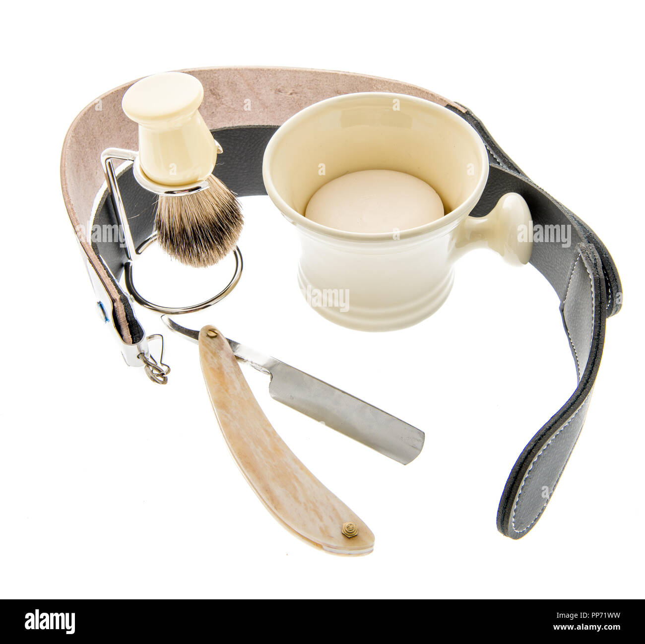 A straight razor with a leather strap for sharpening and brush and cup
