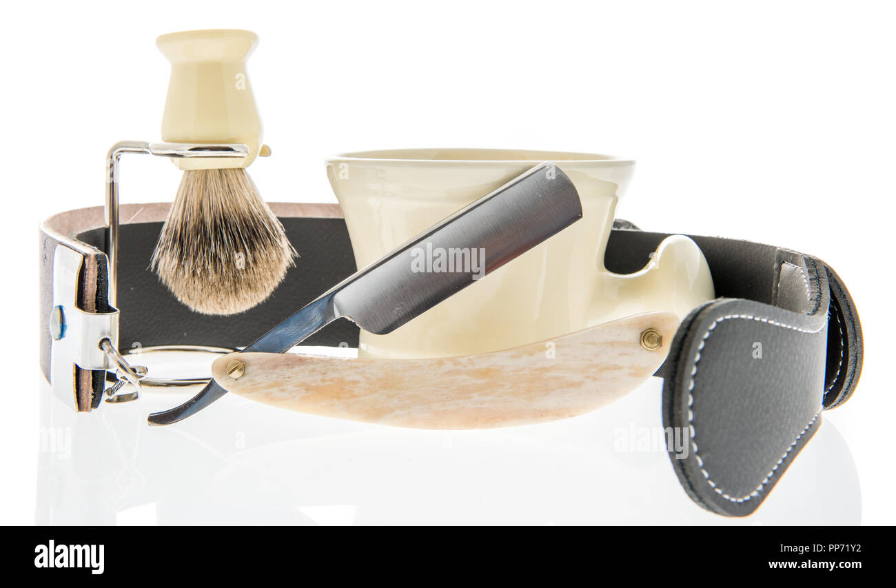 A straight razor with a leather strap for sharpening and brush and cup