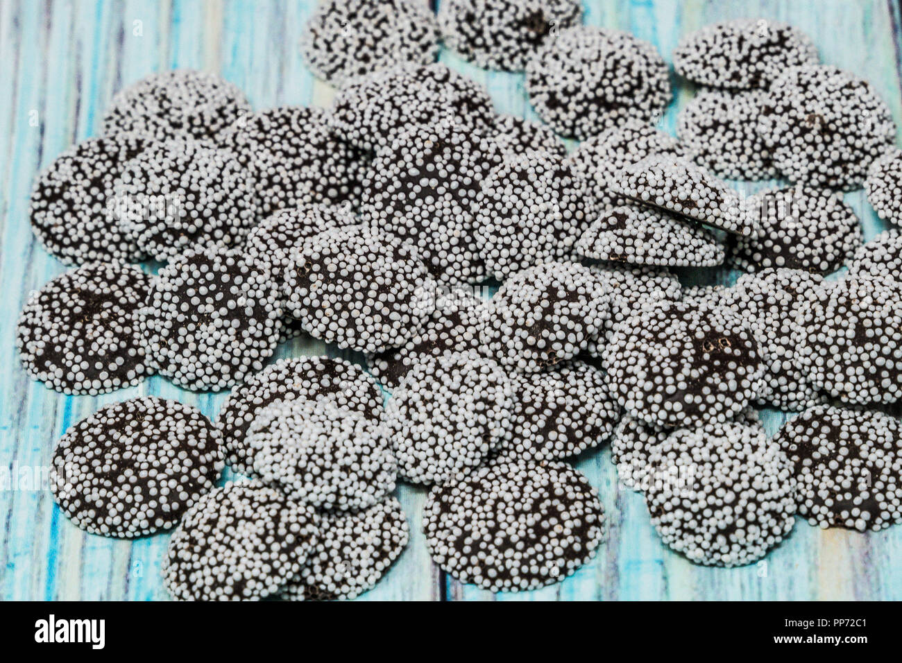 Close up of nonpareils chocolate candy with white sprinkles. Wooden