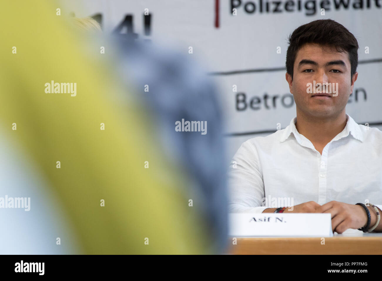 Nuernberg, Bavaria. 24th Sep, 2018. Asif N., a refugee from Afghanistan, sits behind his name tag during a press conference during an upcoming trial after a tumultuous deportation attempt. On May 31, 2017, the then 20-year-old was to be taken into deportation custody from a Nuremberg vocational school. The deployment had attracted attention and criticism nationwide. Credit: Daniel Karmann/dpa/Alamy Live News Stock Photo