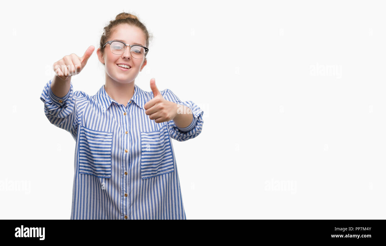 Young blonde business woman approving doing positive gesture with hand, thumbs up smiling and happy for success. Looking at the camera, winner gesture Stock Photo