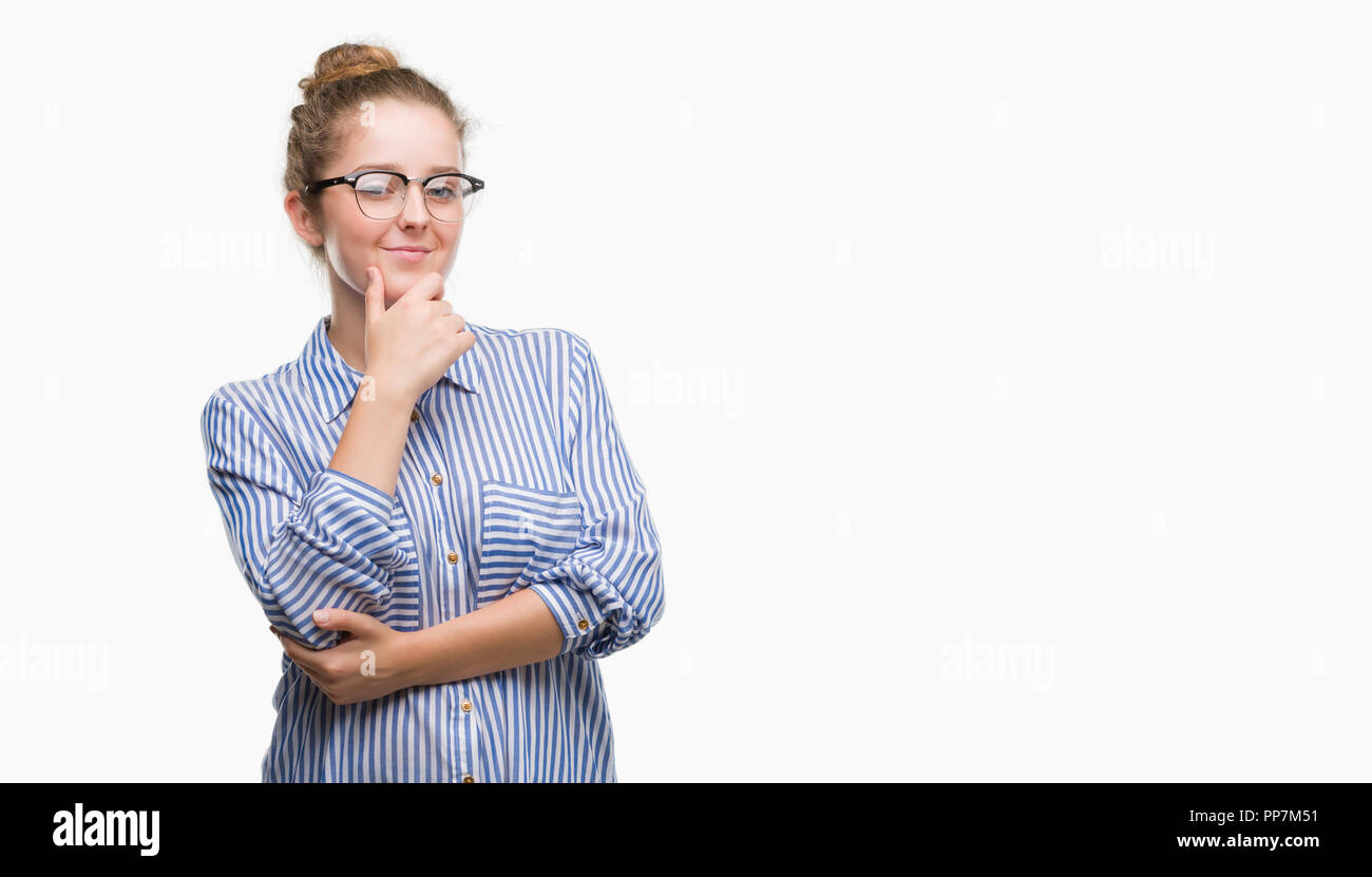 Young blonde business woman looking confident at the camera with smile with crossed arms and hand raised on chin. Thinking positive. Stock Photo