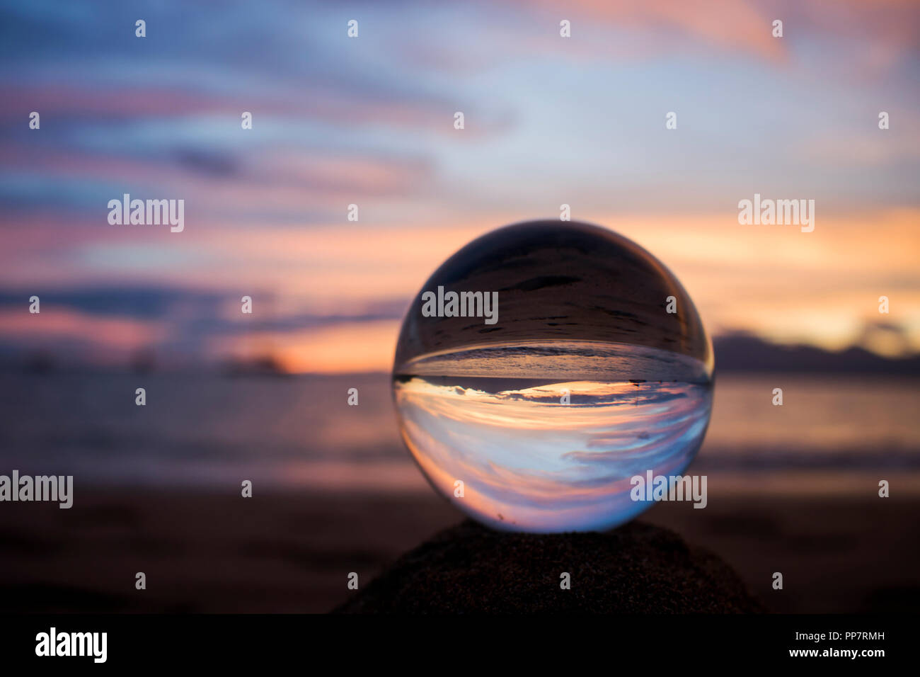 Sunset over Ocean with Reflection Captured in Glass Ball on Sand Stock ...