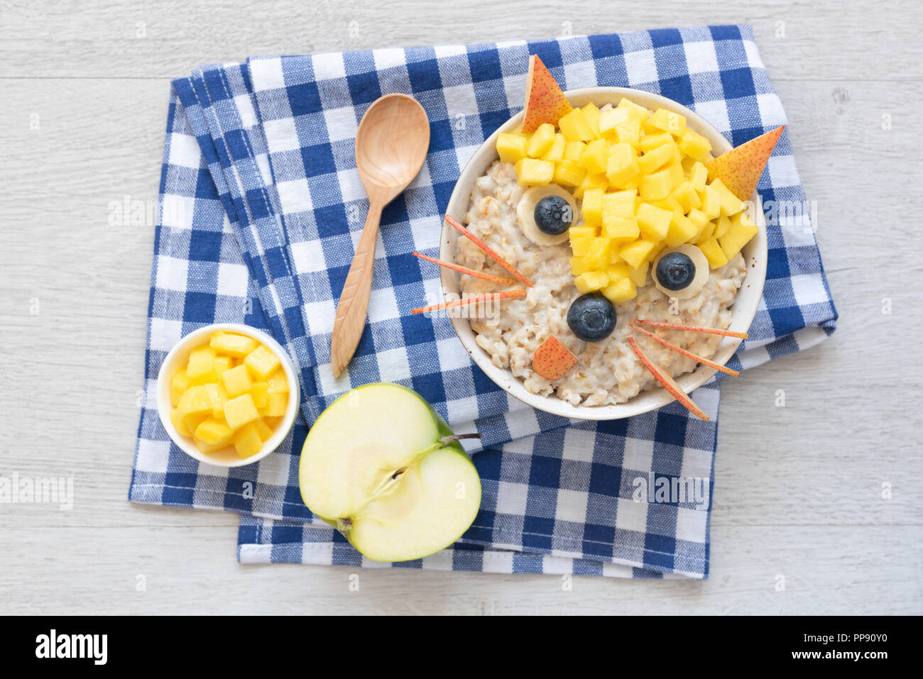 Funny Breakfast For Kids. Oatmeal Porridge With Cute Fruit Face. Porridge with fruits and berries for healthy breakfast Stock Photo