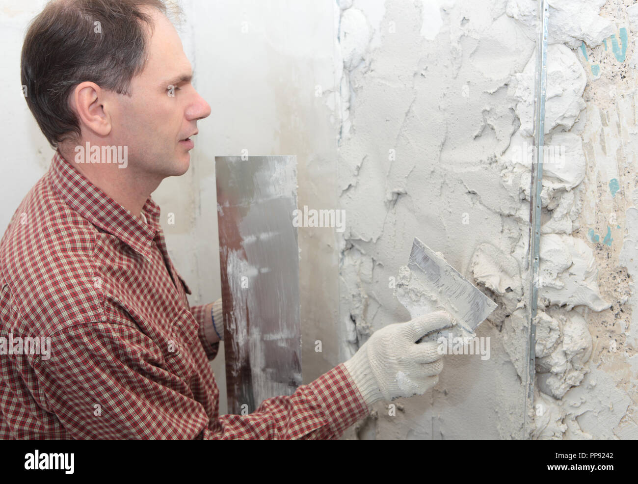 Worker plastering a wall using trowel Stock Photo
