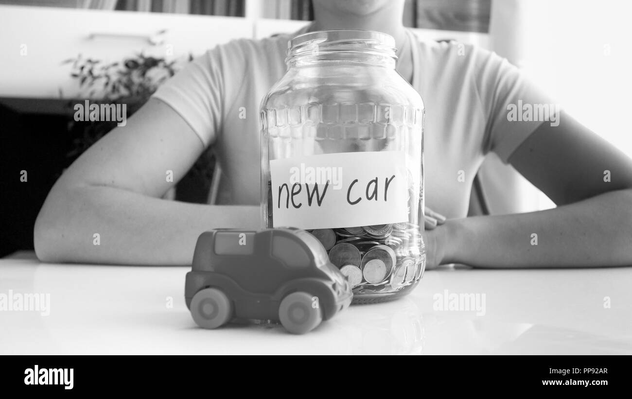 Black and white image of young woman saving money for purchasing new car Stock Photo