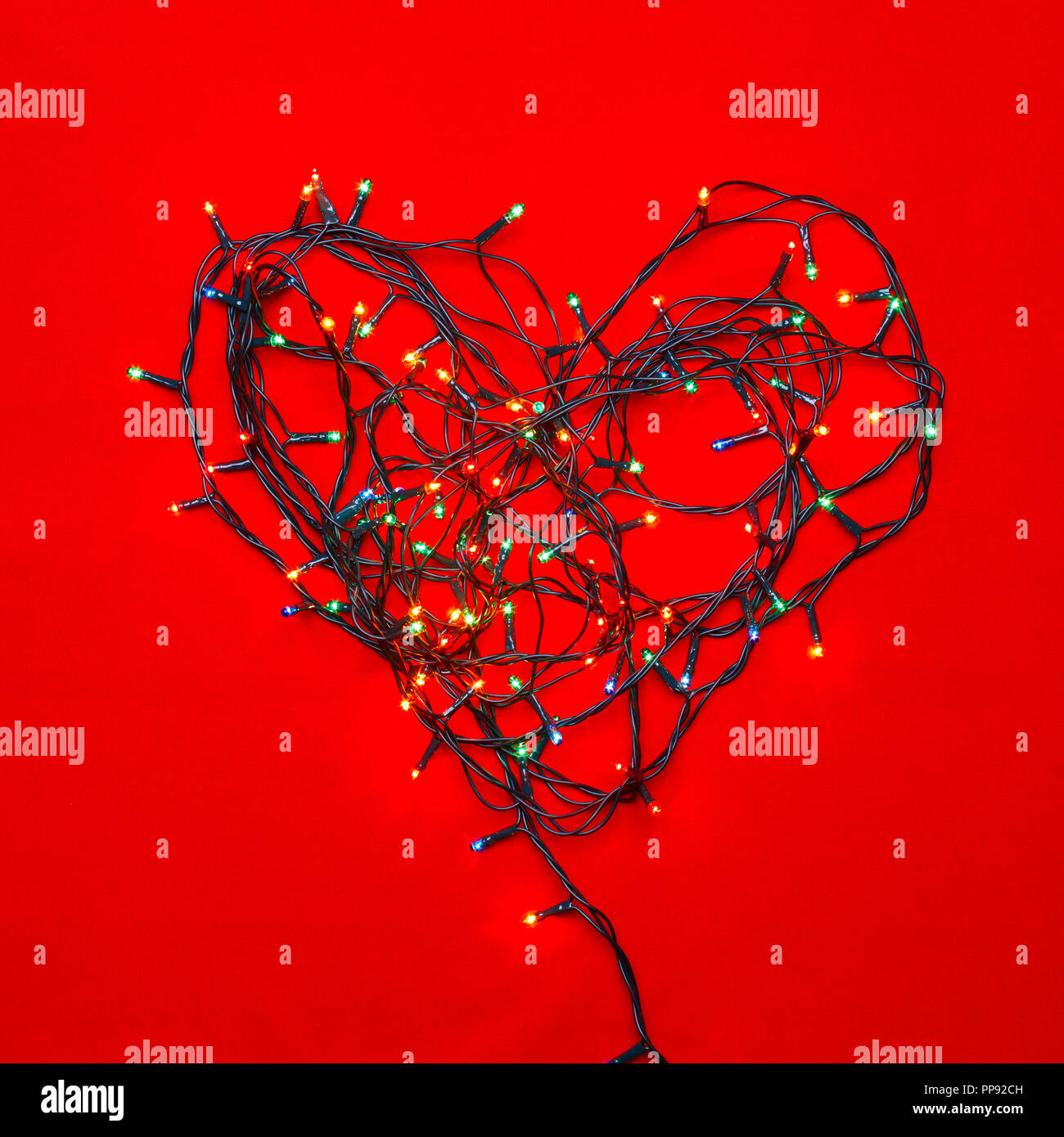 Christmas lights in the shape of heart on red background Stock Photo