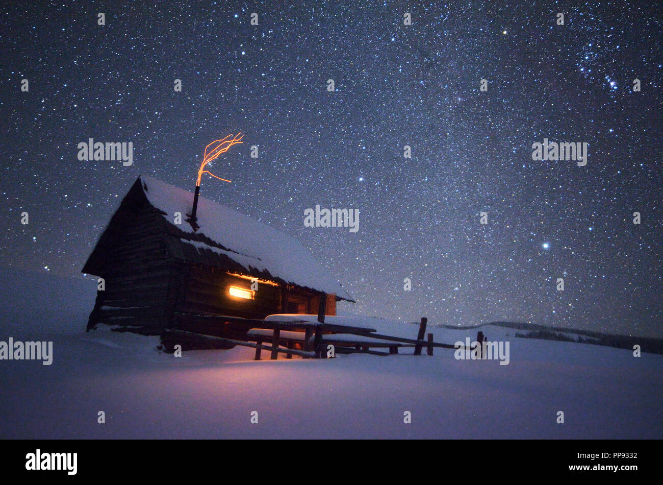 Night with stars. Christmas landscape. Wooden house in the mountain village Stock Photo
